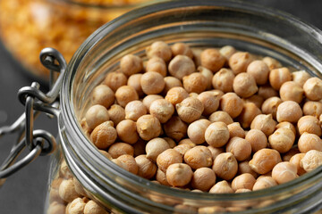 Uncooked dried chickpeas in glass jar close up