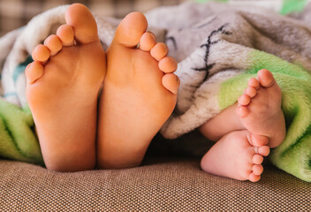 Children's feet peek out from under the blanket. Two children of different ages.