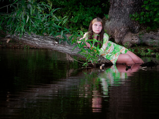 Fototapeta na wymiar girl lies in the water on a branch of an old tree