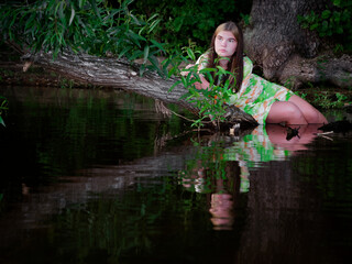 girl lies in the water on a branch of an old tree