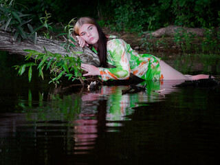 girl lies in the water on a branch of an old tree