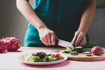 Obraz na płótnie Canvas Woman cutting vegetables preparing for making vegan salad 