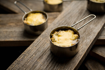 Julienne with chicken, cheese and mushrooms served in small metal bowl. Selective focus. Shallow depth of field.