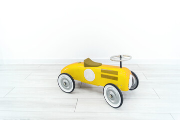 Toy yellow retro car. The child plays with transport.