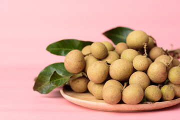 Fresh longan fruit on plate with pink background, Tropical fruit