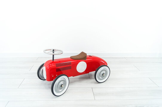 Toy red retro car. The child plays with transport.