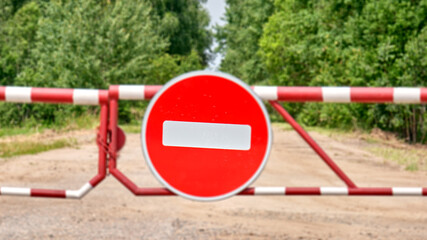 No entry car sign on a blurred  striped barrier against a dirt road, Chernobyl zone 