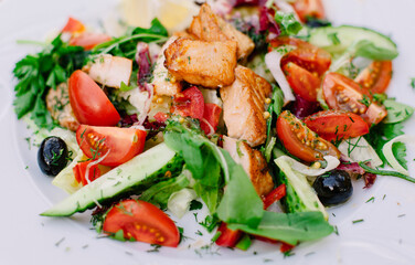 Salad with fresh vegetables, olives and slices of salmon shot in macro 