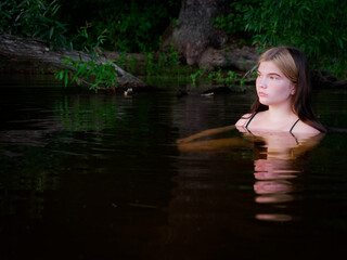 girl is reflected in the dark water at sunset