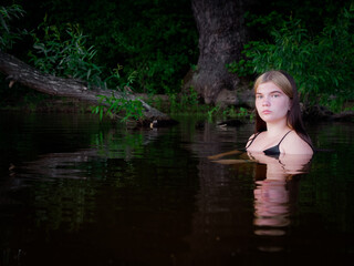 Fototapeta premium girl is reflected in the dark water at sunset
