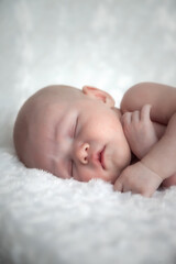 Newborn baby sleeps sweetly on light background. Portrait of month-old baby with tender skin on changing table in room. Close-up of beautiful child on white background. Concept of new life