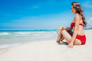 Fototapeta na wymiar Sea beach A beautiful young tanned girl in a red bikini, paradise tropical white sand beach. Pretty woman enjoys the moment being in the Maldives