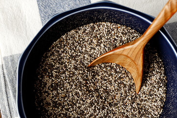 Chia seeds in a bowl with wooden spoon