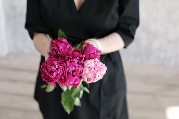 bouquet of red peonies in the florist girl hands. Selective focus