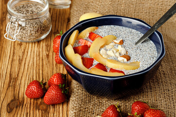 Bowl of chia poudding with pieces of apricots and strawberry