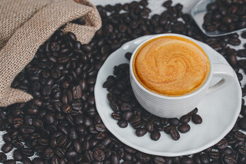 hot espresso and coffee bean on white table with soft-focus and over light in the background. top view