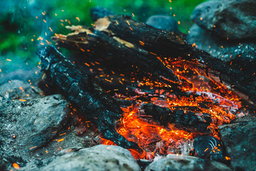 Vivid smoldered firewoods burned in fire closeup. Atmospheric background with orange flame of...
