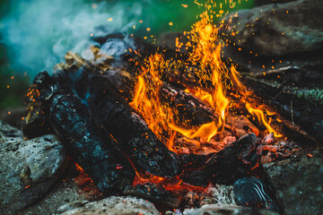 Vivid smoldered firewoods burned in fire close-up. Atmospheric background with orange flame of...