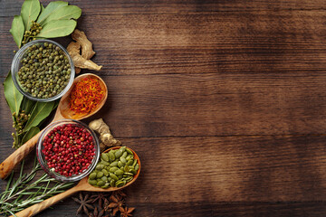 Vivid colorful spices in wooden spoons on wooden background