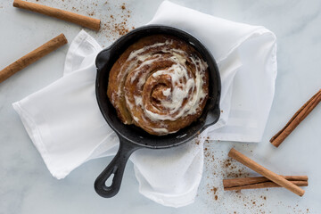 Cinnamon bun baked in cast iron fry pan skillet.