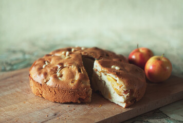 Apple pie with nuts and two apples behind on the kitchen table