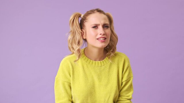 A delightful girl cannot hear her interlocutor due to hearing problems, isolated in a studio on a purple background