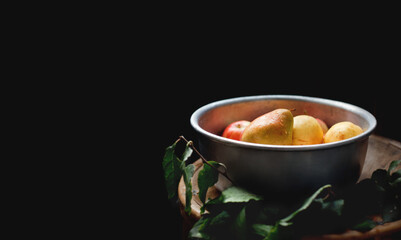 Fresh fruits floating in the metal basin on a black background. Autumn harvest in rustic style