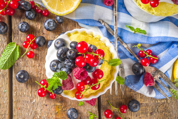 Lemon Mug Cake. Summer sweet dessert in  Microwave. Lemon Mug Pies with fresh berries and whipped cream, on wooden background