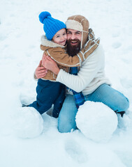 Daddy and boy smiling and hugging. Cute son hugs his dad on winter holiday. Merry Christmas and Happy New Year. Christmas Celebration holiday. Winter portrait of dad and child in snow Garden.