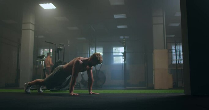 a strong purposeful man performs push-UPS despite fatigue and pain overcoming difficulties. the concept of a healthy lifestyle
