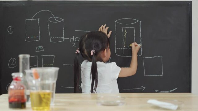 Asian little girl is writing the mobility of color by the chromatography principle on the blackboard at home, concept of homeschooling and learn through play activity for kid education.