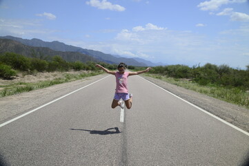 Chica sola saltando alegre en la ruta