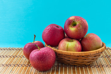 Apples in a wicker basket on a blue background.