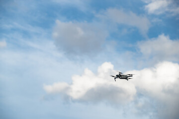The flying soaring drone in the sky, the blue sky with white clouds, sunny weather, Turning propellers, nobody