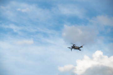 The flying soaring drone in the sky, the blue sky with white clouds, sunny weather, Turning propellers, nobody