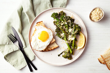 Roasted broccolini with fried egg on the plate.