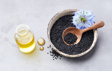 Obraz na płótnie Canvas Black cumin seeds with nigella sativa flower on gray background