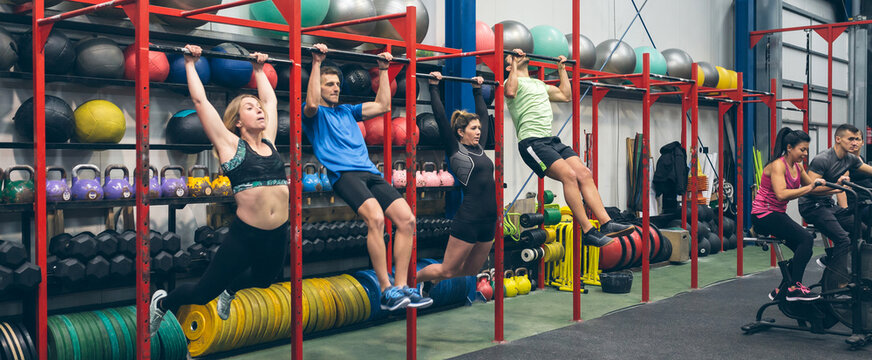 Athletes Doing Pull Ups And Air Bike In The Gym