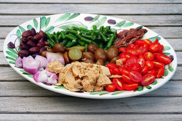 A nicoise salad with canned tuna, anchovies, tomatoes, potatoes and vegetable