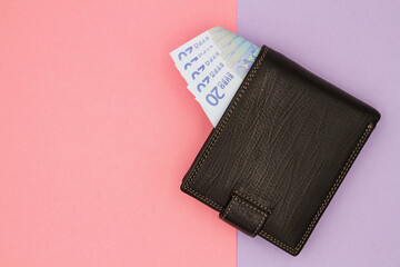 Close-up of black wallet with 20 Euro banknotes on a colored background