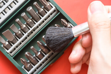 Close up photo of hand cleaning a Drill bit set on red background