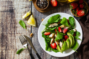 Lunch for keto. Summer salad with strawberries, grilled chicken and avocado on a rustic table. Top view flat lay background. Copy space.