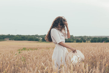 
Girl puts a hat on a wheat field, girl plays with her hat on a field