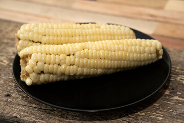 Yellow boiled corn placed on a black plate