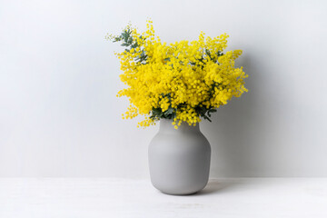 A beautiful floral arrangement of Australian native yellow wattle/acacia flowers in a grey vase on...