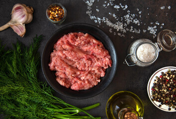 Homemade minced meat in a black bowl with ingredients. Fresh Raw mince. Top view