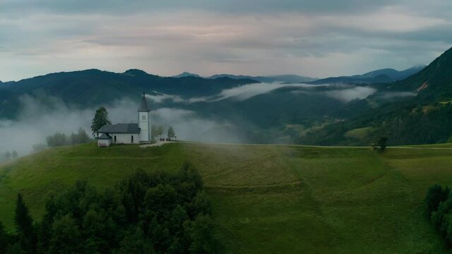 Jamnik, Slovenia - 4K aerial drone footage of flying slowly towards St.Primoz church on a foggy summer morning