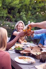 Friends Making Toast With Alcohol In Garden At Home Enjoying Summer Garden Party