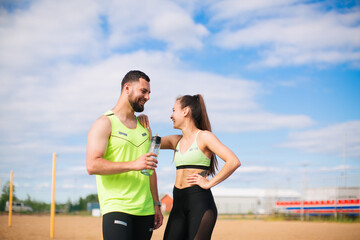 Athletic couple girl and man fitness instructors rest and drink water after street training, photo for sport blog or ad