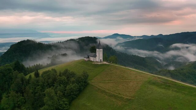 Jamnik, Slovenia - Aerial time-lapse (hyperlapse) footage of drone flying by St Primoz church on a foggy summer morning in the Upper Carniola region of Slovenia